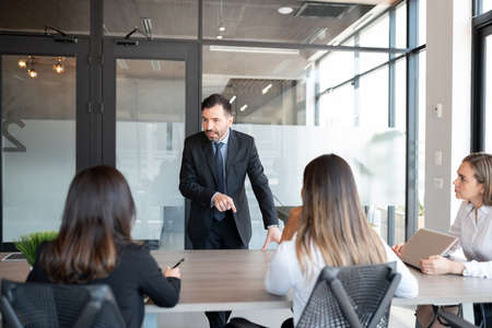 Mature businessman addressing to team of professionals in meeting roomの写真素材