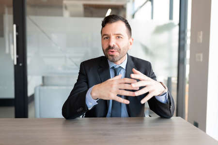 Businessman in suit talking to camera during a web conference in office