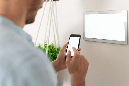 Closeup of a young man connecting his smartphone to his smart home system