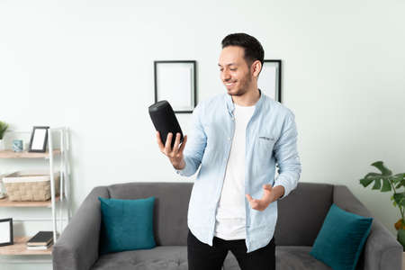 Portrait of a good looking man holding up his new smart speaker and ready to set it up in his...