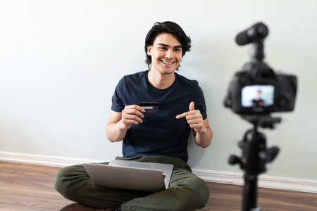 Good looking Latin man and influencer recommending his bank and pointing at his new credit card and...