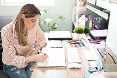Attractive female illustrator doing a sketch on a notepad while working in her officeの写真素材