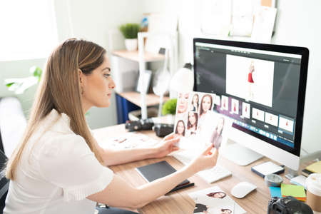 Pretty Caucasian photographer comparing poses and photos from a recent fashion shootの写真素材