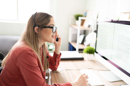 Profile view of a woman working as an interpreter while looking at some documents and wearing a...