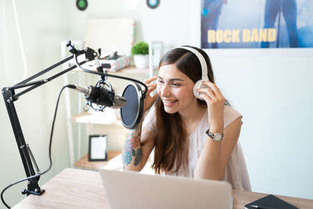 Pretty female announcer talking to some of her fans and online audience while broadcasting a live...