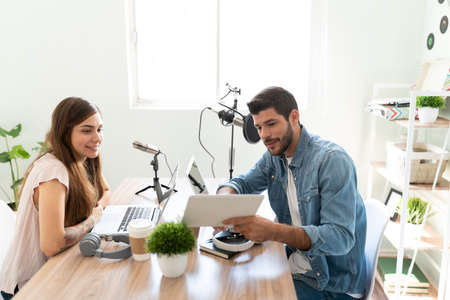 Blogger and invited guest looking at some photos and data during an interview in a live podcast for social mediaの写真素材