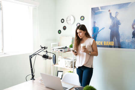 Beautiful girl working in a radio station and  checking on social media before going live on her...