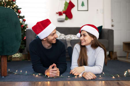 Boyfriend and girlfriend looking at each other while lying on the floor at home during Christmas
