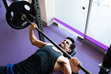 Athletic young man about to lift a heavy weight bar at the fitness centerの写真素材
