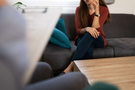 Close up of a woman in her 20s talking about her psychological problems with a psychiatrist during a therapy sessionの写真素材