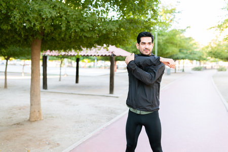 Young man wearing sporty clothes stretching his arms before starting his morning run in the parkの写真素材