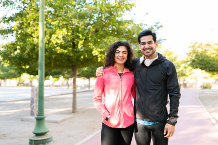 Happy sporty couple wearing activwear. Good-looking young man and young woman hugging after working out in the parkの写真素材