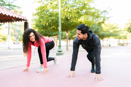 Happy fitness couple laughing and preparing to start a running race in the parkの写真素材