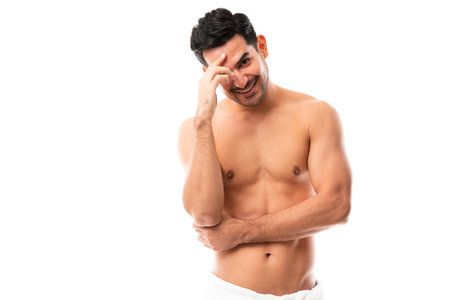 Good looking young man with muscular body standing in towel on white backgroundの写真素材