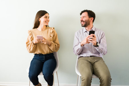 Attractive man in his 30s and woman in his 20s sitting together and smiling. Couple participating on a speed dating eventの写真素材