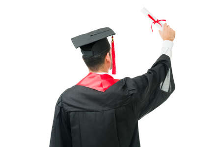 Smart man in his 20s seen from behind while raising his university diploma during his graduation ceremony. Happy young graduate celebrating after receiving his college certificateの写真素材