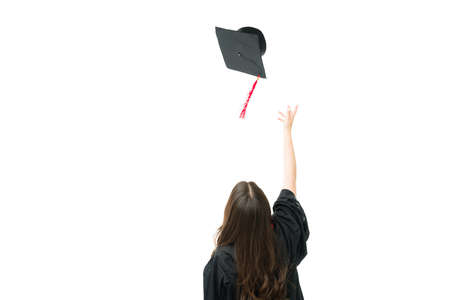 Young woman seen from behind wearing a graduation gown and throwing a cap in the air after receiving a university diploma during the commencement exercisesの写真素材