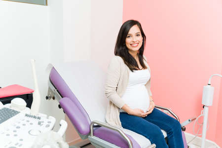 Beautiful pregnant woman waiting for her check up at her gynecologist. Expectant mother sitting on...