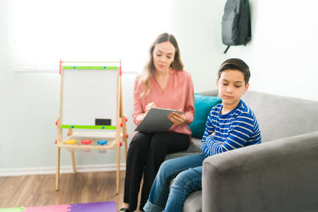 Rude little boy ignoring his female psychologist and doesn't want to speak to her. Elementary boy...