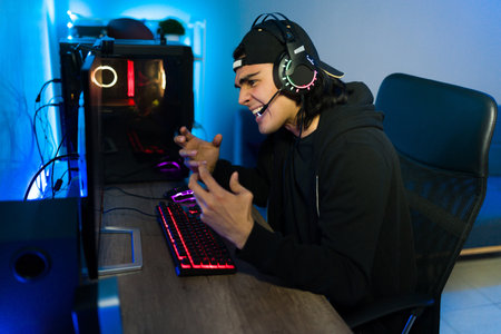Angry latin man screaming at the screen and getting mad after losing an online video game on his...
