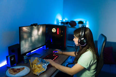 Pretty woman concentrating on an online video game and having fun with a gaming computer. Female...