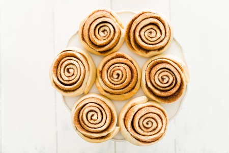 Top view of a lot of perfect and beautiful cinnamon rolls out of the oven and cooling on a cake...