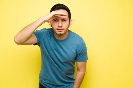 Handsome young man looking something far away. Latin man trying to view ahead and blocking the light...