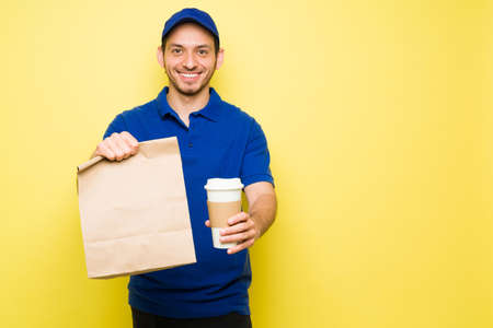 Attractive man working and delivering takeout food on a brown bag with a coffee to go. Delivery...