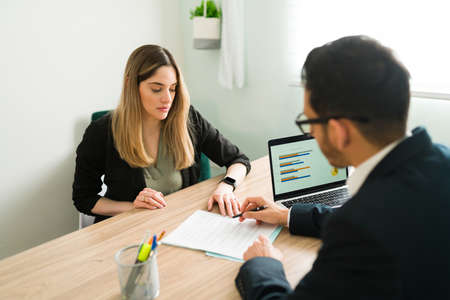 Professional lawyer explaining and reviewing a business contract with a female client at the office. Caucasian woman listening to her male boss talk about a work reportの写真素材
