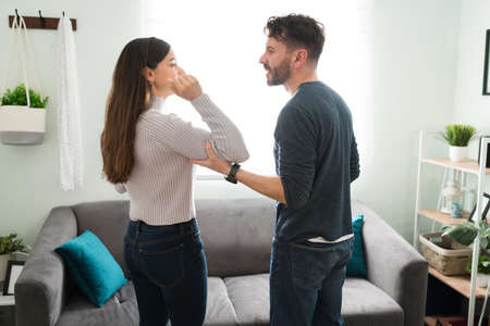 Side view of an angry hispanic man in his 30s grabbing the arm of his young wife during a fight and discussion at home. Domestic violence concept