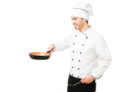 Young chef cooking a delicious dinner at a restaurant. Attractive latin cook frying a new dish with...