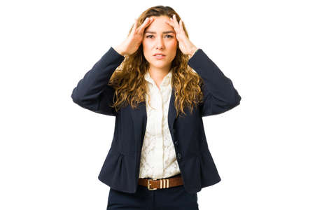 Worried young woman having a bad headache or migraine because of her stressful professional work....