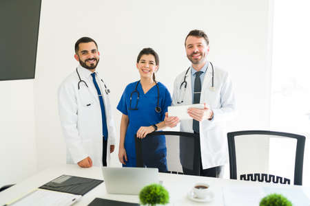 What a rewarding job. Portrait of three happy members of the medical board smiling and making eye contact while standing in the meeting roomの写真素材