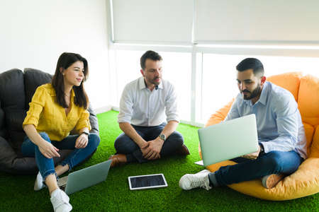 Busy co-workers working together and doing collaborative teamwork while sitting in puff chairs....