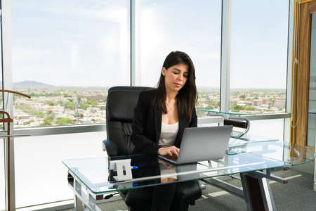Successful and busy female boss working hard to achieve her business goals while typing on her...