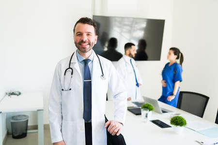 Portrait of a handsome hospital director in a white coat and a stethoscope smiling before starting a...