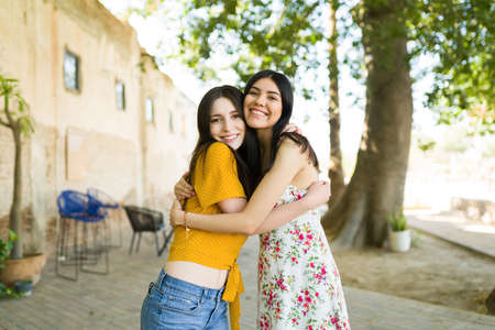 Everything is better together. Beautiful female best friends hugging and giving each other love while hanging out in the parkの写真素材
