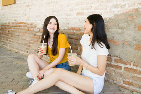 Beautiful female best friends having a nice conversation and talking about their lives while relaxing outdoors during a summer eveningの写真素材