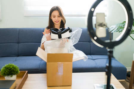 Showing you my new virtual reality glasses. Excited young girl and influencer unboxing a gaming headset while recording a review onlineの写真素材