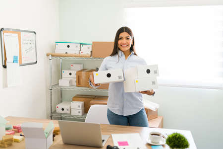 We have a lot of customers orders. Female entrepreneur holding a lot of packages while feeling happy...