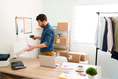 Hardworking entrepreneur using a scanner and scanning the shipping label barcode of a package with...