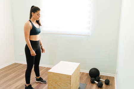 Active woman in sportswear preparing at home to start her functional training and HIIT workout with...