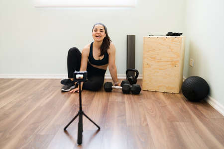 Online workout sessions. Female excited fitness coach laughing and recording exercises lessons for...