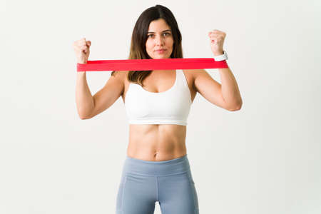 Feeling motivated during a workout. Athletic young woman holding a red resistance rubber band on her...