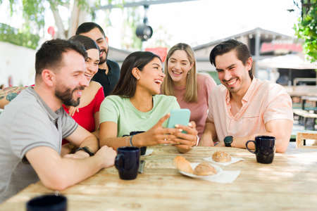 Looking at online content. Diverse group of friends laughing and paying attention to a funny picture...