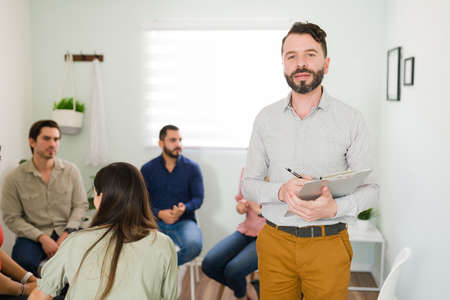 Portrait of a mental health counselor ready to start a group therapy meeting. Hispanic leader beginning a session of an addiction support groupの写真素材