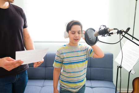 Memorizing the lyrics of the song. Talented young boy learning a new song with his private music teacher during singing lessons at homeの写真素材
