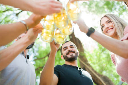 Happy friends making a toast with beer. Young women and men celebrating together and enjoying some...