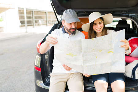 Latin handsome man and young woman smiling while looking at a big map to plan a route for their...