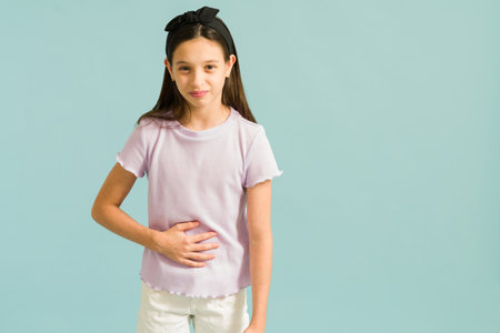 I am not feeling well. Portrait shot of a sick young girl rubbing her belly and suffering from pain because of a stomach acheの写真素材